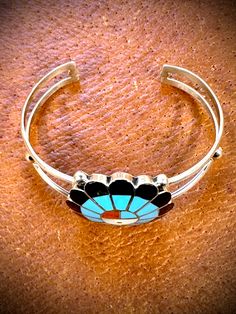 What a sensational piece of jewelry. This Sunface cuff depicts the ancient Zuni symbol that represents the sacred Sun Father of the Zuni culture. A piece that can be worn with any ensemble or maybe an addition to a collection. 2 1/2" long x 1 1/2" wide Artisan Nickel-free Bangle, Artisan Bangle Jewelry Collectible, Turquoise Symbolic Adjustable Jewelry, Southwestern Style Round Cuff Bracelet As Gift, Southwestern Style Jewelry Bracelet With Inlay, Adjustable Artisan Jewelry With Inlay, Southwestern Nickel-free Bangle Jewelry, Unique Adjustable Jewelry With Inlay, Nickel-free Southwestern Style Bangle