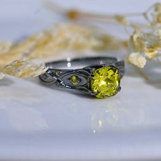 a yellow diamond ring sitting on top of a white plate next to dried flowers and leaves