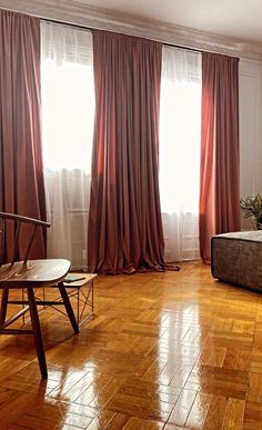 an empty room with wooden floors and curtains