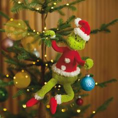 a christmas ornament is hanging from a tree with lights in the background and a dr seuss hat on it