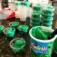 green jello in plastic cups on a counter