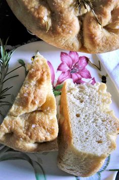 two pieces of bread on a plate with flowers and rosemary sprigs next to it