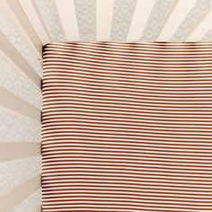 a brown and white striped crib sheet in a baby's nursery bedding