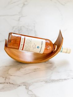 a bottle of wine sitting on top of a wooden boat shaped tray with writing on it