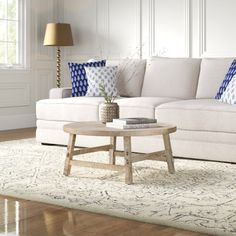 a living room with white furniture and blue pillows on the couches, along with a coffee table