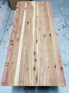 a table made out of wood sitting on top of a cement floor next to a cardboard box