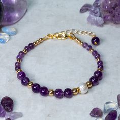 Amethyst, Freshwater Pearl and gold Hematite asymmetric gemstone bracelet designed and handcrafted with care and attention to detail using: AAA 6mm and 4mm genuine Amethyst beads, Beautiful Freshwater Pearl, AAAAA 4mm and 3mm 18ct gold plated Hematite beads. The bracelet is constructed using quality 19 strand nylon coated beading wire which is both flexible and extremely durable. The bracelet measures 19cm and is fastened using an 18ct gold plated lobster claw clasp and 30mm extension chain for Spiritual Amethyst Gold Bracelets, Gold Amethyst Beaded Bracelets, Gold Amethyst Bracelets For Healing, Gold Bracelets With Round Amethyst Beads, Gold Amethyst Beaded Bracelets For Jewelry Making, Gold Beaded Amethyst Bracelets, Gold Amethyst Gemstone Bracelets, Gold Amethyst Crystal Bracelet With Natural Stones, Elegant Gold Amethyst Crystal Bracelet