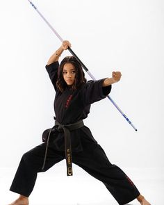 a woman is doing karate with two swords in her hand and one arm raised up