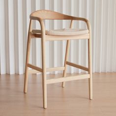 a wooden chair sitting on top of a hard wood floor next to a white curtain