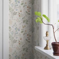 a potted plant sitting on top of a window sill next to a wall paper