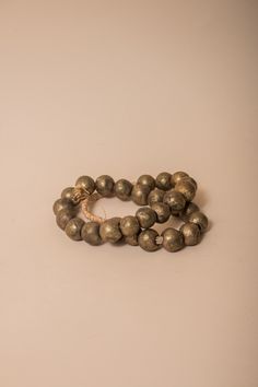 These brass African beads are beautifully textured, each individual bead unique in shape and finish for a final look that feels one-of-a-kind and natural. Perfect for layering on a vase, an open book, a bowl, or styling on a shelf. All Sales Final Free Shipping Brass Beaded Bracelets With Round Beads, Brass Bracelets With Round Gold Beads, Artisan Gold Bracelets With Polished Beads, Gold Brass Beaded Bracelets With Round Beads, Gold Artisan Bracelet With Polished Beads, Gold Round Brass Beaded Bracelets, Gold Bracelets With Wooden Beads For Healing, Artisan Gold Bracelets With Round Beads, Gold Earthy Beaded Bracelets With Round Beads