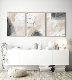 two abstract paintings hang on the wall above a white cabinet in a modern living room