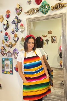 a woman standing in front of a mirror wearing an apron