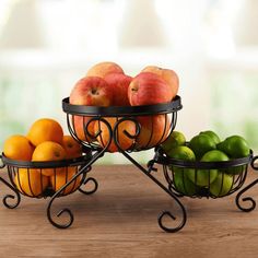 two metal bowls filled with fruit on top of a wooden table