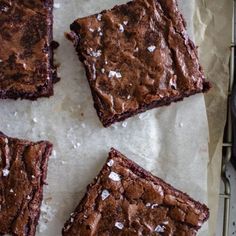 four brownies sitting on top of a piece of parchment paper