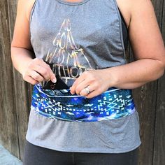 a woman in grey tank top holding cell phone and wearing blue bandana waist belt