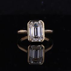 an emerald cut diamond sits on top of a black surface