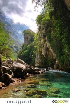 a river surrounded by mountains and trees with the words wander trek tocht picos de europe