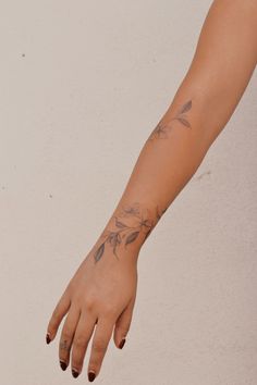 a woman's arm with tattoos on it and her hand holding something in the air