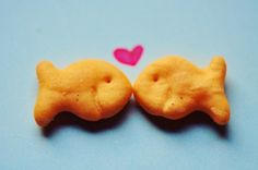 two heart shaped cookies sitting next to each other on a blue surface with pink hearts