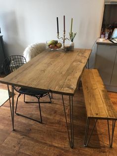 a wooden table with metal legs and two benches in the middle of a living room