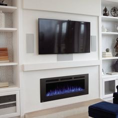 a living room with a large television mounted on the wall next to a fire place