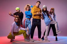 a group of young people posing for a photo in front of a pink background stock photos