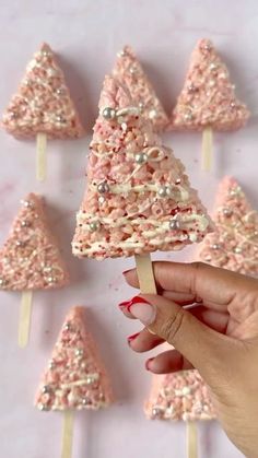 a hand holding a toothpick with pink and white sprinkles on it