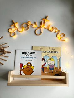 two children's books sit on a shelf under a lit up sign that reads, little miss doubter