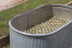 a metal tub filled with hay next to a wooden fence