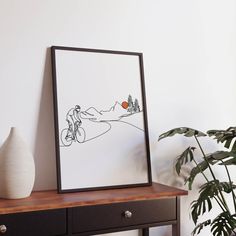 an art piece on a table next to a potted plant and a framed photo