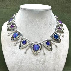 Here's a striking new necklace of handmade dichroic glass cabochons. They are set into fine silver bezels on domed, sterling, triangular drops. The domed drops are suspended on twisted and hammered wire links with silver granulation. A stunning accessory for special occasions. The video shows how some of the dichroic glass cabochons shift color as they move through different lighting, from blue and purple to pink and orange. It is light weight and comfortable to wear. The necklace is 19.75 inche Silver Drop Glass Jewelry, Silver Teardrop Glass Necklaces, Unique Iridescent Cabochon Necklaces, Silver Glass Drop Jewelry, Silver Glass Teardrop Jewelry, Silver Drop Necklace With Cabochon, Silver Glass Jewelry With Gemstone, Silver Glass Gemstone Jewelry, Silver Teardrop Necklaces With Unique Variations