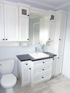 a bathroom with white cabinets and black counter tops