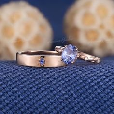 two gold wedding rings with tan and blue sapphire stones on the sides, sitting on top of a blue cloth