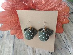 a pair of polka dot cup earrings on top of a piece of paper next to an orange flower