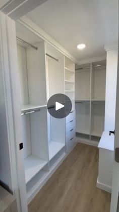 an empty walk in closet with white shelves and drawers on the wall, next to a wooden floor