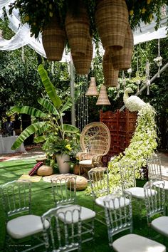 chairs and tables are set up in the grass for an outdoor wedding ceremony with hanging wicker baskets above them