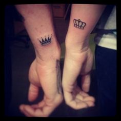 two people holding hands with tattoos on their arms and one has a crown tattooed on the wrist