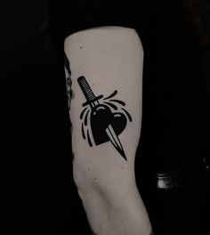 a black and white tattoo on the arm of a person with a knife in it