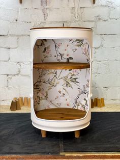 a white and wooden shelf with floral print on the top, against a brick wall