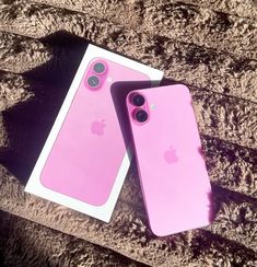 two pink iphones sitting next to each other on top of a carpeted floor