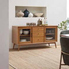 a dining room table with plates and vases on the top shelf, next to an open cabinet