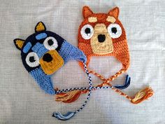 two crocheted hats with eyes and ears on top of a white cloth background