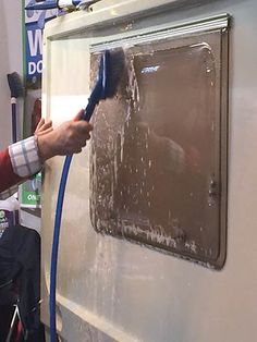 a man is using a brush to clean the side of a truck's door