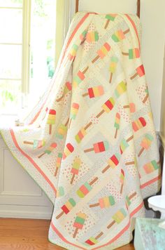 an ice cream themed quilt on a chair in front of a window with sun coming through