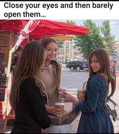 three girls are standing outside talking to each other and one is holding a coffee cup