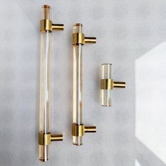 three brass and glass door handles on a white wall