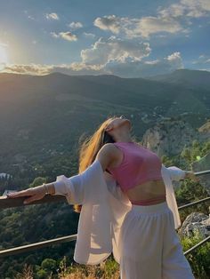 a woman standing on top of a hill with her arms outstretched