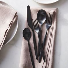 black utensils are sitting on a napkin next to silverware