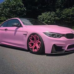 a pink car is parked on the side of the road in front of some trees